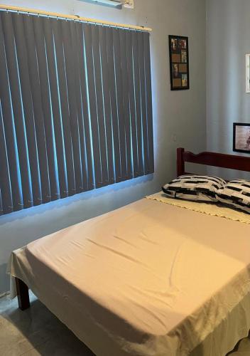 a bed in a bedroom with a window with blinds at Casa Gui in São Gabriel