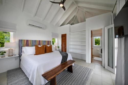 una camera da letto bianca con un letto e una panca di Villa Santorini a Enighed