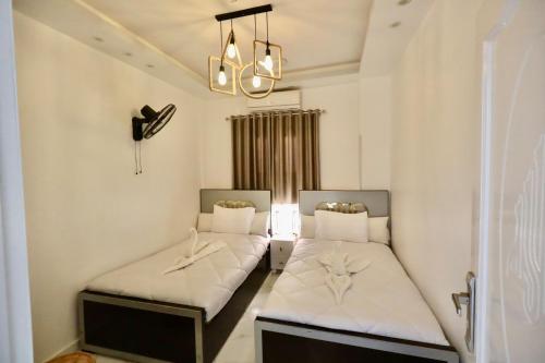 two beds in a small room with a chandelier at White Gorf Hotel in Luxor