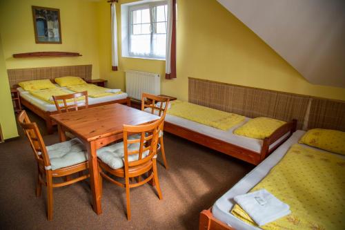 Zimmer mit 4 Betten, Tisch und Stühlen in der Unterkunft Hotel Sirákov in Liptál