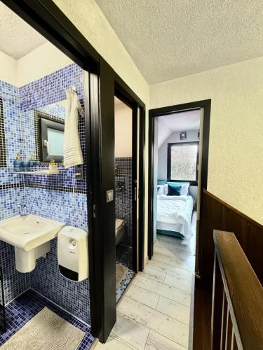 a blue tiled bathroom with a sink and a bed at RestOnTheLake in Esztergom