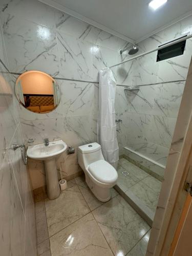 a white bathroom with a toilet and a sink at Deptos Helen in Termas de Río Hondo