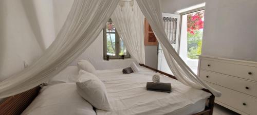 a white bed with curtains in a bedroom at Villa Mikro Chorio in Kóstos