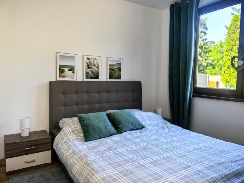 a bedroom with a bed with a blue comforter and a window at SAN ESCOBAR sauna jacuzzi jezioro in Rogowo