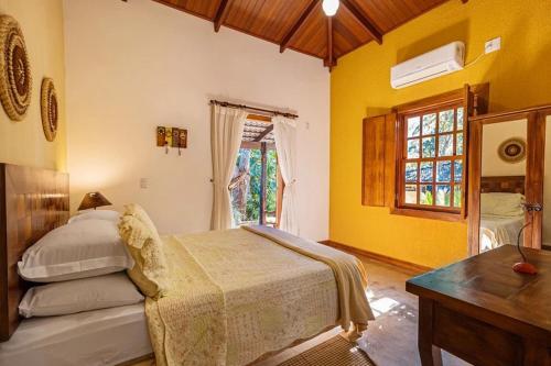 a bedroom with a bed and a desk and a window at Casas Solar dos Pireneus in Pirenópolis