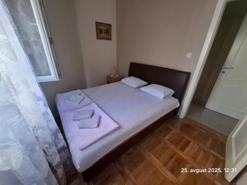 a small bedroom with a bed with pink sheets and pillows at Topla in Herceg-Novi