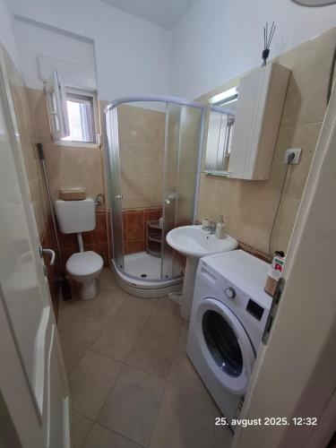 a bathroom with a shower toilet and a washing machine at Topla in Herceg-Novi