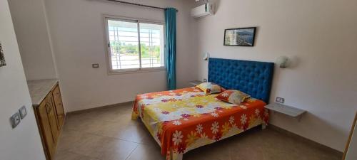 a bedroom with a bed with a blue headboard and a window at Excellent Appartement S plus 3 in Kelibia