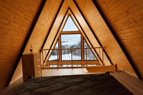 ein Bett in einem Zimmer mit einem großen Fenster in der Unterkunft Roua A-frame in Deal