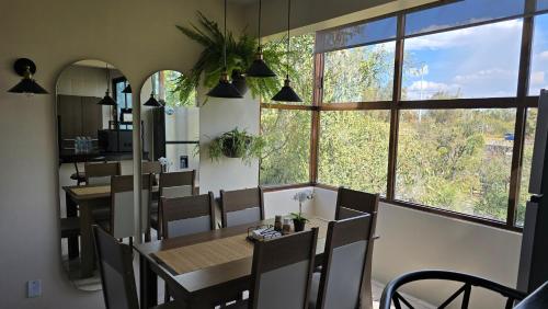 a dining room with a table and chairs and windows at Departamento acogedor in Mexico City