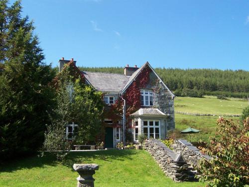 a house on a hill with a grass yard at Penmachno Hall - self catering suite in Betws-y-coed