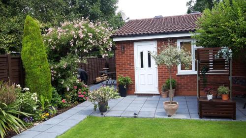 a brick house with a white door in a garden at Apartment in Solihull, near B'ham, NEC & Warwick in Solihull