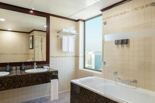 a bathroom with two sinks and a tub and a window at Sheraton The Walk, Dubai in Dubai