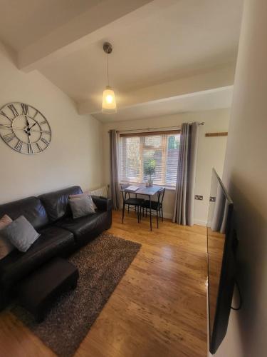 a living room with a couch and a table with a clock at Apartment in Solihull, near B'ham, NEC & Warwick in Solihull