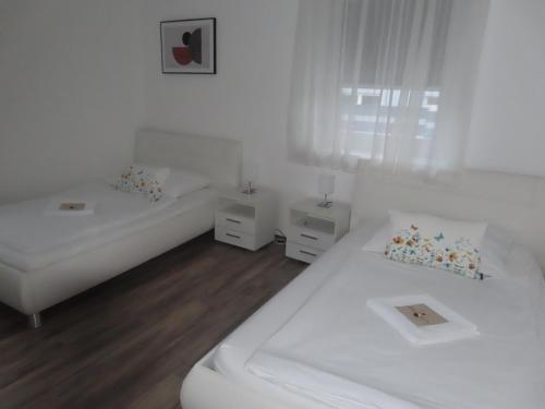 a white room with two beds and two night stands at Apartment Vlora-Naturblick in Villach