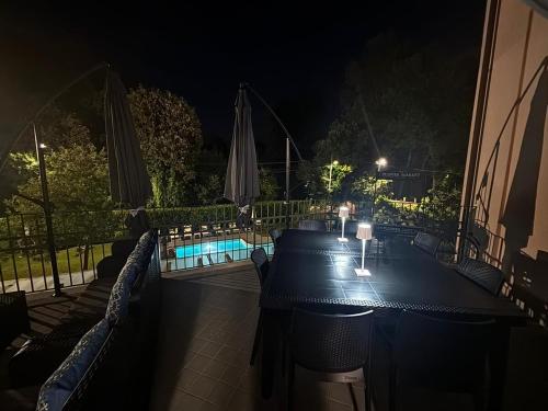 a table with chairs and a swimming pool at night at Lightblue in Marina di Massa