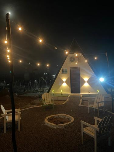 a tent with chairs and a fire pit at night at Chalé serra da formiga in Riachuelo
