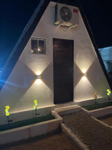 a white building with a black door and lights at Chalé serra da formiga in Riachuelo
