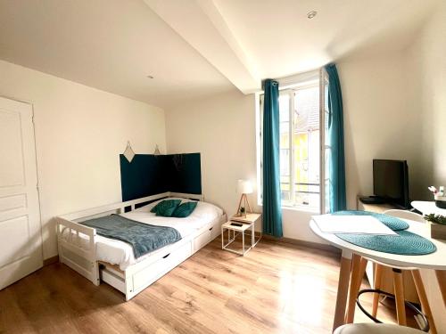 a bedroom with a white bed and a table at Le Blue- hyper centre ville in Sens