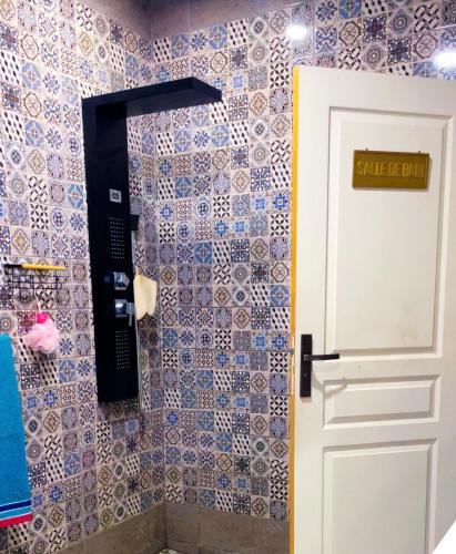 a bathroom with a door and a tiled wall at Villa bleu azur in Djerba