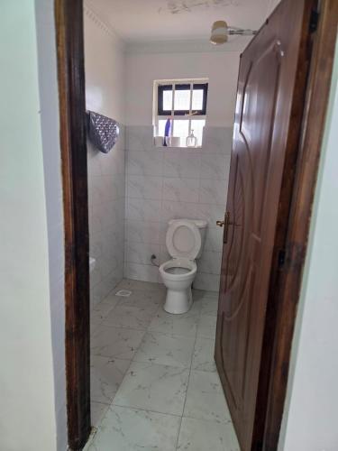 a bathroom with a toilet and a window at Waridi Homes One-bedroom Naivegas Apartment in Naivasha