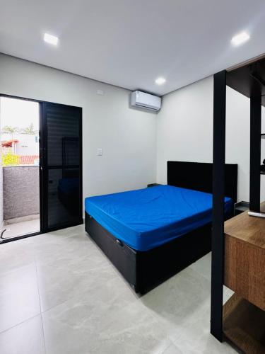 a bedroom with a blue bed in a room at Sobrados Novos Litoral Norte Caraguatatuba, a 150 m a pe da Praia das Palmeiras, Ar condicionado, WiFi gratis, Churrasqueira privativa, Pet friendly, Estacionamento in Caraguatatuba