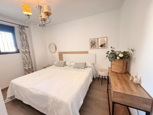 a white bedroom with a bed and a table at New Caleta apartment seaviews in Caleta De Velez