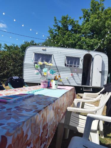 Caravane cocooning في Saint-Martin-des-Noyers: طاولة أمام مقطورة عليها خيمة