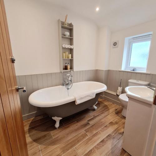 a bathroom with a bath tub and a toilet at Chy Bownder Cottage in Lostwithiel