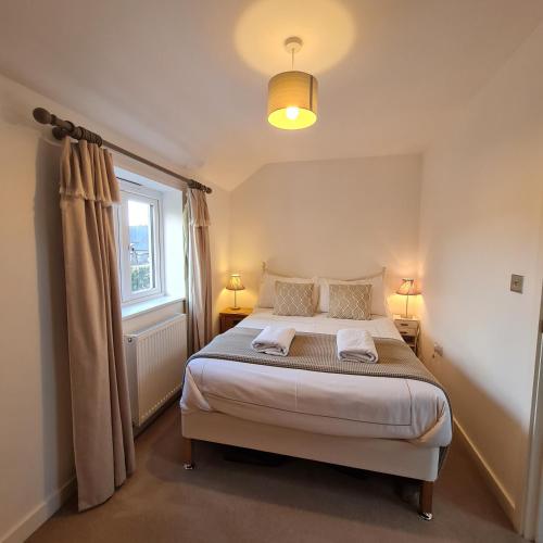 a bedroom with a bed with two pillows and a window at Chy Bownder Cottage in Lostwithiel
