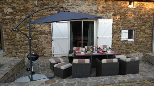 a table with chairs and an umbrella on a patio at Les Fougères Du Lac in Saint-Plantaire