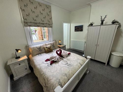 a bedroom with a bed with a red ribbon on it at The Sandbed Retreat in Hawick