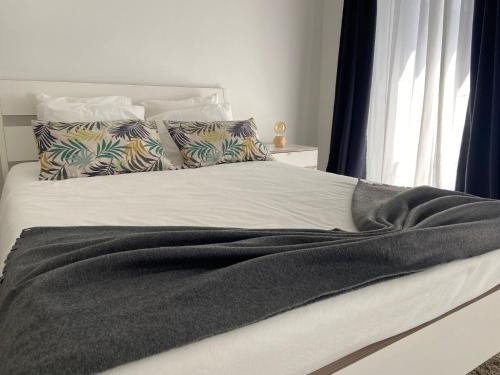 a bed with a black blanket and pillows on it at A Casinha in Angra do Heroísmo
