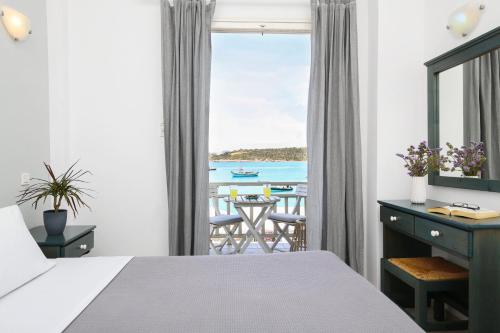 a bedroom with a bed and a view of the ocean at Angeliki Seaside Hotel in Aliki