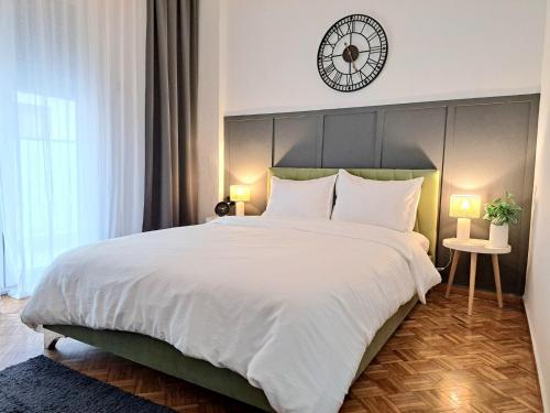 a bedroom with a large bed with a clock on the wall at Stylish City Center Apartment - with FREE PARKING space -not for big cars- 200m away in Serres