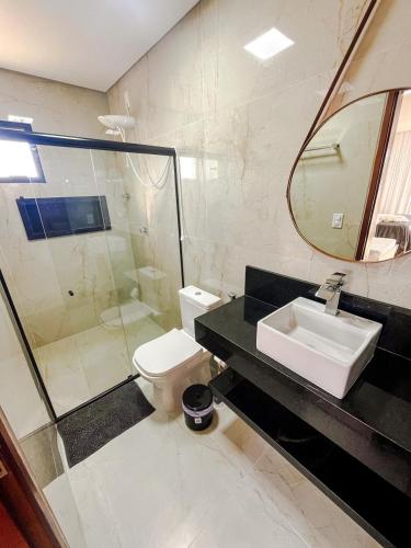 a bathroom with a sink and a toilet and a mirror at Casa Aconchegante em Japaratinga in Japaratinga