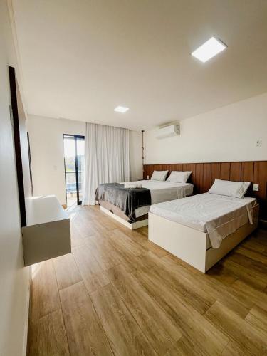 two beds in a large room with wooden floors at Casa Aconchegante em Japaratinga in Japaratinga