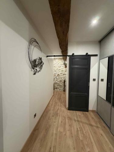 a hallway with a black door and a stone wall at Au rêve de Fadi in Bruch