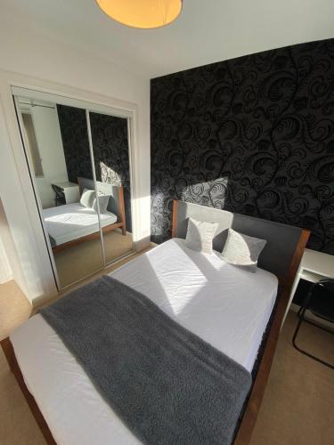 a bedroom with a large bed and a mirror at One double en-suite room at seaside flat in Aberdeen