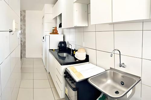 a kitchen with white cabinets and a sink and a refrigerator at Vacanze - Alicante in Maceió