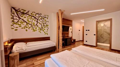a bedroom with two beds and a tree mural at Hotel Cristallo in Canazei