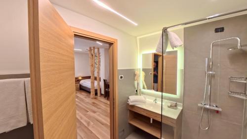 a bathroom with a walk in shower and a sink at Hotel Cristallo in Canazei