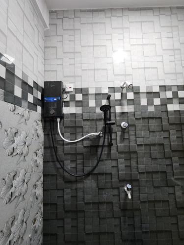 a shower in a bathroom with a tiled wall at Mahizh Manai in Jaffna