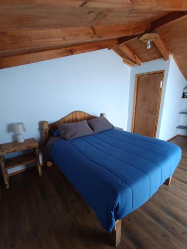 a blue bed in a room with a wooden ceiling at Casa playa Pullay in Pullay