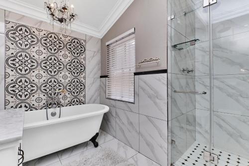 a bathroom with a tub and a glass shower at Frnch on 2nd - Sandton in Johannesburg