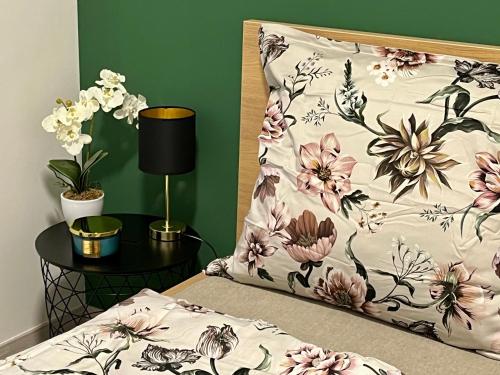 a bed with a floral pillow and a table with a lamp at Interno Casa in Sopron
