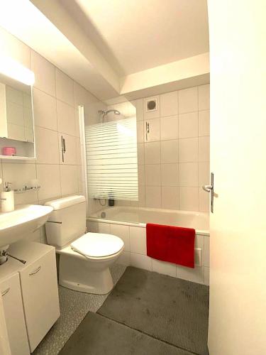 a bathroom with a white toilet and a red towel at 3-Room Apartment Up to 5 Guests Family Business Free WiFi Netflix Sky DAZN Disney Plus 1000 International TV Channels in Wynau