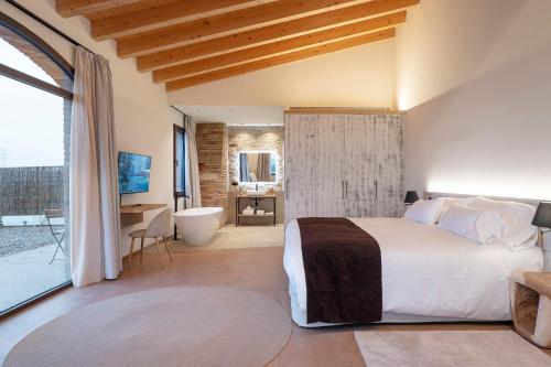 a bedroom with a large bed and a bathroom at Hotel Mas Vidal Vilafreser in Vilademuls