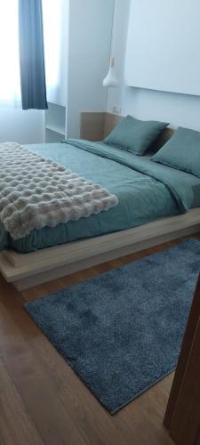 a bedroom with a bed with a blue rug at Apartement LUNA Hotel Zlatni javor in Jahorina