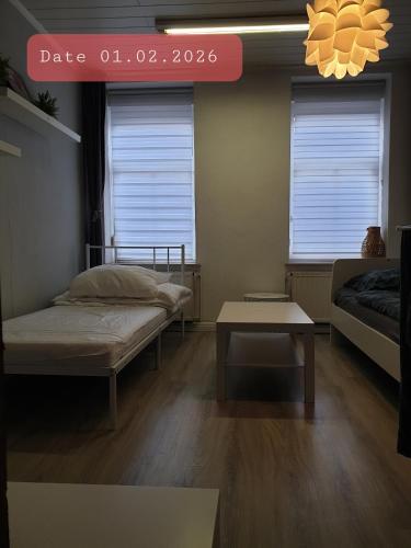 a room with two beds and a table and windows at FeWo Nina - Monteurwohnung in Weißenfels